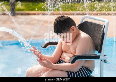 Child with cerebral palsy playing in splash pad Stock Photo