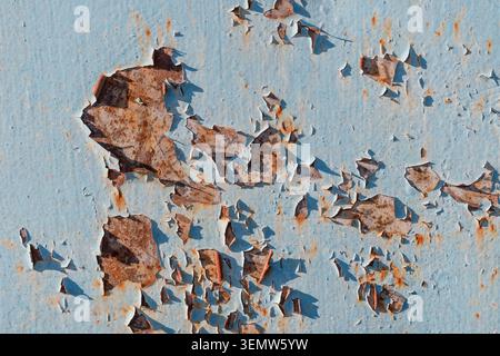 Rusty metal texture with cracked peeling blue paint. Grunge background of weathered iron plate with industrial corrosion and paint flakes. Stock Photo