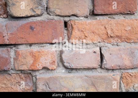 A detailed full frame view of an old weathered red clay brick wall texture with rough cement joints for historical construction backgrounds Stock Photo