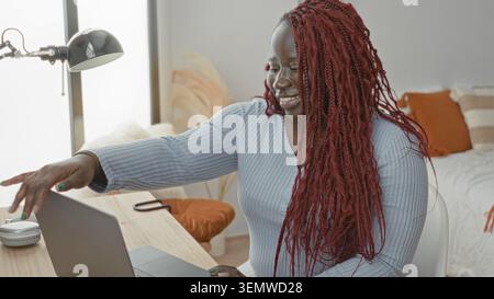 Young woman closing laptop with hands on desk in bedroom, smiling and leaning back after finishing work; relief break. Stock Photo