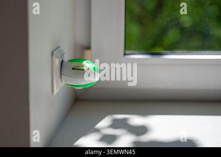 Home protection against mosquitoes, electric fumigator repellent plugged in socket on wall at window Stock Photo