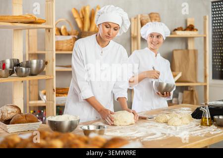Female bakers in uniform preparing gray dough Stock Photo