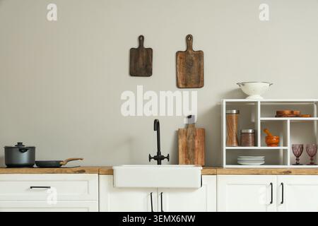 White kitchen counters with sink, utensils and houseplant near white wall Stock Photo