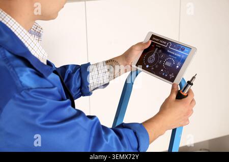 Male worker with tablet installing alarm system in house, closeup Stock Photo