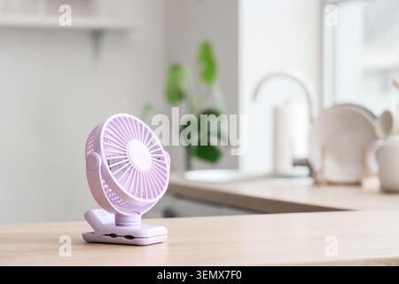 Lilac mini fan on table in kitchen, closeup Stock Photo