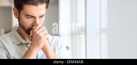 Thoughtful young man pondering serious decisions, experiencing stress and anxiety, facing challenges and uncertainty Stock Photo