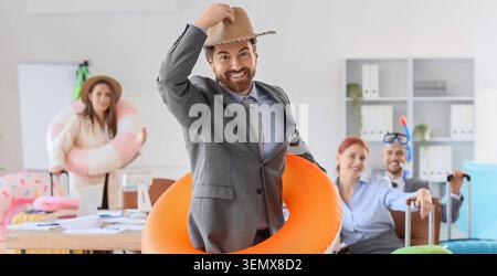 Happy business people in office with vacation accessories, summer holiday planning, and work-life balance Stock Photo