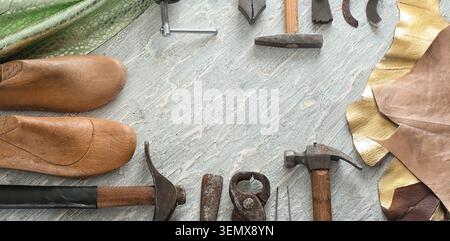 Traditional shoemaking craftsmanship with vintage cobbler tools, wooden shoe lasts, and leather materials on a textured background Stock Photo