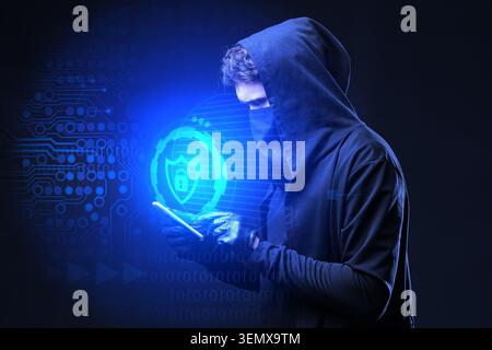 Cybersecurity threat: hooded hacker using smartphone with digital lock icon on dark blue background, a hooded hacker uses a smartphone with a glowing Stock Photo
