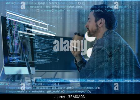 Focused male programmer drinking coffee while coding on computer, software development and data analysis Stock Photo