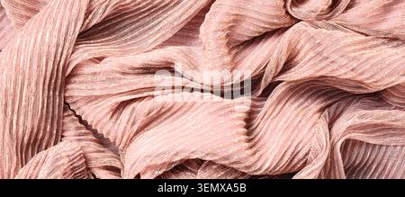 Elegant rose gold shimmer fabric texture with pleated folds and metallic threads, luxurious textile background, the abstract pattern features elegant Stock Photo