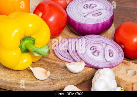 Sliced red onion, tomatoes, garlic, and sweet pepper in close-up on a wooden background. Stock Photo