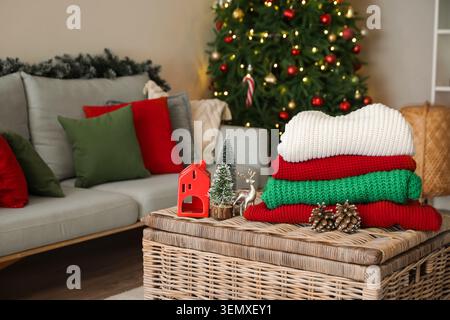 Stack of winter clothes with Christmas decorations on wicker table at home Stock Photo