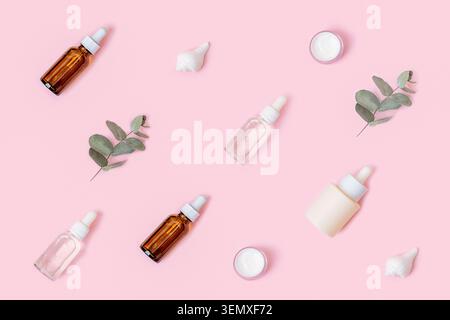 Pattern of skincare products and eucalyptus leaves on pink background. Natural cosmetics concept, top view Stock Photo