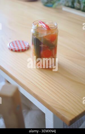 Pickled vegetables in a jar on a wooden table Stock Photo