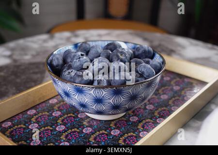 Bowl of blueberries on a marble table in a cozy setting Stock Photo