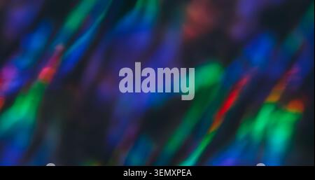Refraction flare. Blur rainbow light. Defocused green orange blue multicolor lens glow shine sparkle flicker on abstract dark black background. Stock Photo