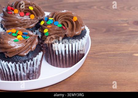 Muffins topped with chocolate cream and sprinkled with colorful candy bits. Stock Photo