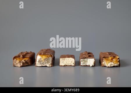 Five broken chocolate bars with assorted fillings on a gray background Stock Photo