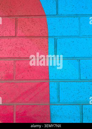 A wall features two sections, one red and one blue, creating a bright visual contrast. The sunlight enhances the colors of the paint and reveals the t Stock Photo