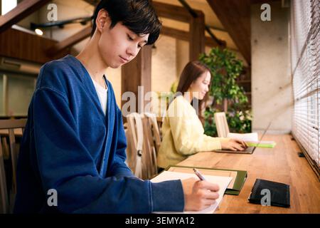 Japanese male and female university students studying seriously at a campus cafe Stock Photo
