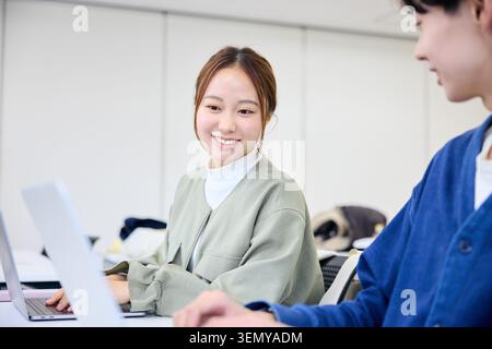 Smiling Japanese university students learning with laptops in a classroom Stock Photo