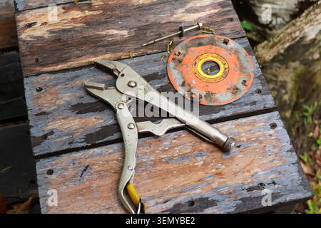 Vintage metal plier, rusty blade, and manual tool rest on weathered wood surface inside quiet workshop, evoking nostalgic mood and memories of traditi Stock Photo