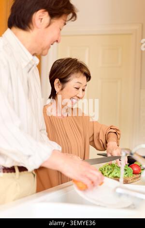 Happy Japanese senior couple preparing vegetables in kitchen Stock Photo