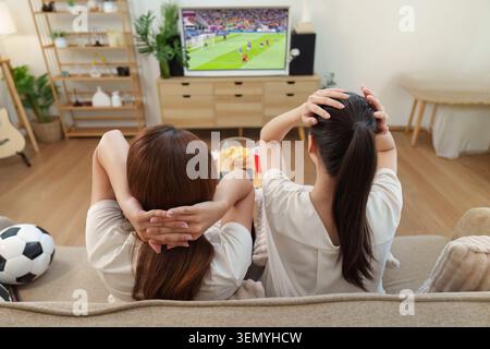 Asian women relaxing watching football match on television at home Stock Photo