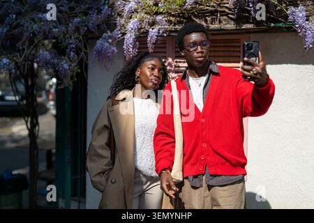 Stylish african american man and woman students pose for selfie outdoors on street together. Stock Photo
