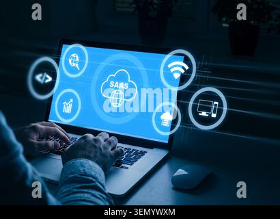 Working on a laptop with SaaS applications in a modern digital workspace at night Stock Photo
