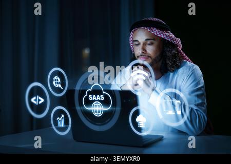 Person uses laptop for Software as a Service tasks in a dark room at night Stock Photo