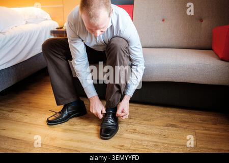 Man preparing for a meeting, dressing formal attire in a modern hotel room Stock Photo