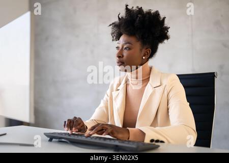 Young successful business woman using a computer while working in a startup company office Stock Photo