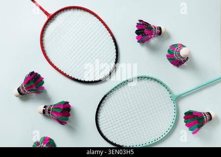 Colorful feather badminton shuttlecocks and two badminton rackets on light blue background. View from above. Copy space. Concept racket sport. Leisure games. Stock Photo
