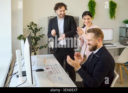 Happy colleagues celebrating achievement after successful office analytics results Stock Photo