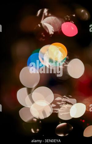Colorful bokeh lights on a dark background creating an abstract festive effect. Stock Photo