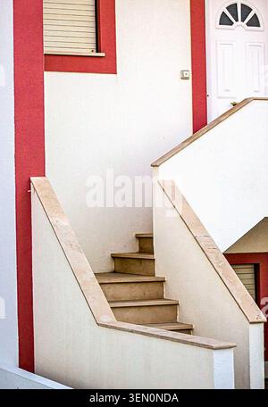 Clean architectural detail featuring an exterior staircase, geometric lines, and a white facade with coral accents in a residential building in Portug Stock Photo