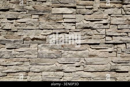 Old stone cladding wall made of striped stacked slabs of gray brownish rocks. Outdoor coating. Background and texture. Stock Photo