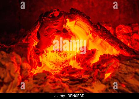 Glowing embers with intense heat and vibrant red-orange hues in a dark setting. Stock Photo