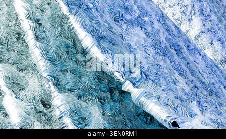 Abstract close-up of blue and white textured patterns in a layered wave-like design. Stock Photo