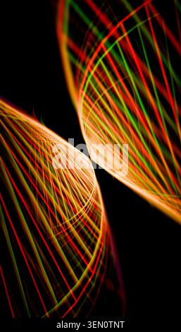 Intersecting vibrant light trails with red and green hues in a dynamic pattern on black. Stock Photo