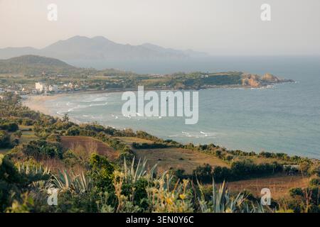 Serene coastal landscape with distant mountains and a sandy beach in the golden sunlight. Stock Photo