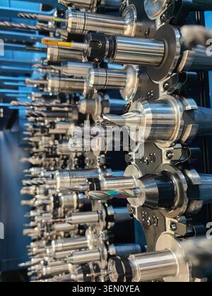 Close-up of various cutting tools and holders arranged in the tool magazine of a large CNC milling machine. Precision engineering and metalworking Stock Photo