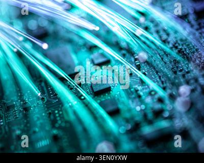 Close-up of a circuit board with glowing fiber optic cables in blue light. Stock Photo