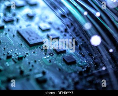 Close-up of a circuit board with microchips and glowing fiber optic cables. Stock Photo
