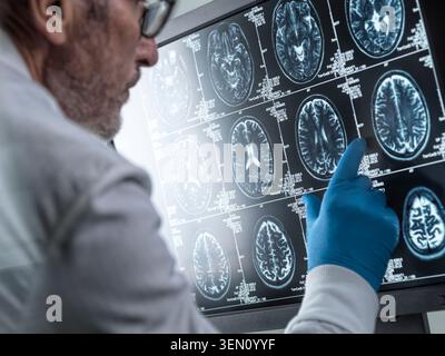 Doctor analyzing MRI brain scans on a screen with focus and precision. Stock Photo