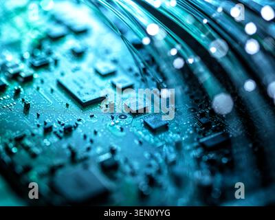 Close-up of a circuit board with glowing fiber optic cables in blue light. Stock Photo