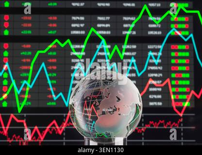 Glass globe in front of a fluctuating stock market graph display with vibrant colors. Stock Photo