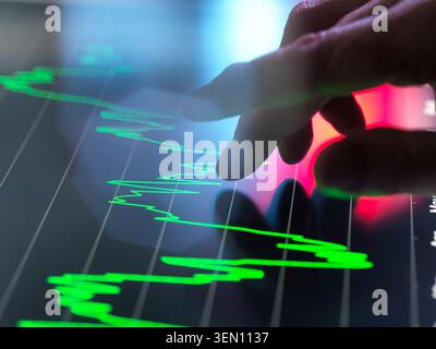 Hand interacts with financial graph on a touchscreen in a high-tech setting. Stock Photo